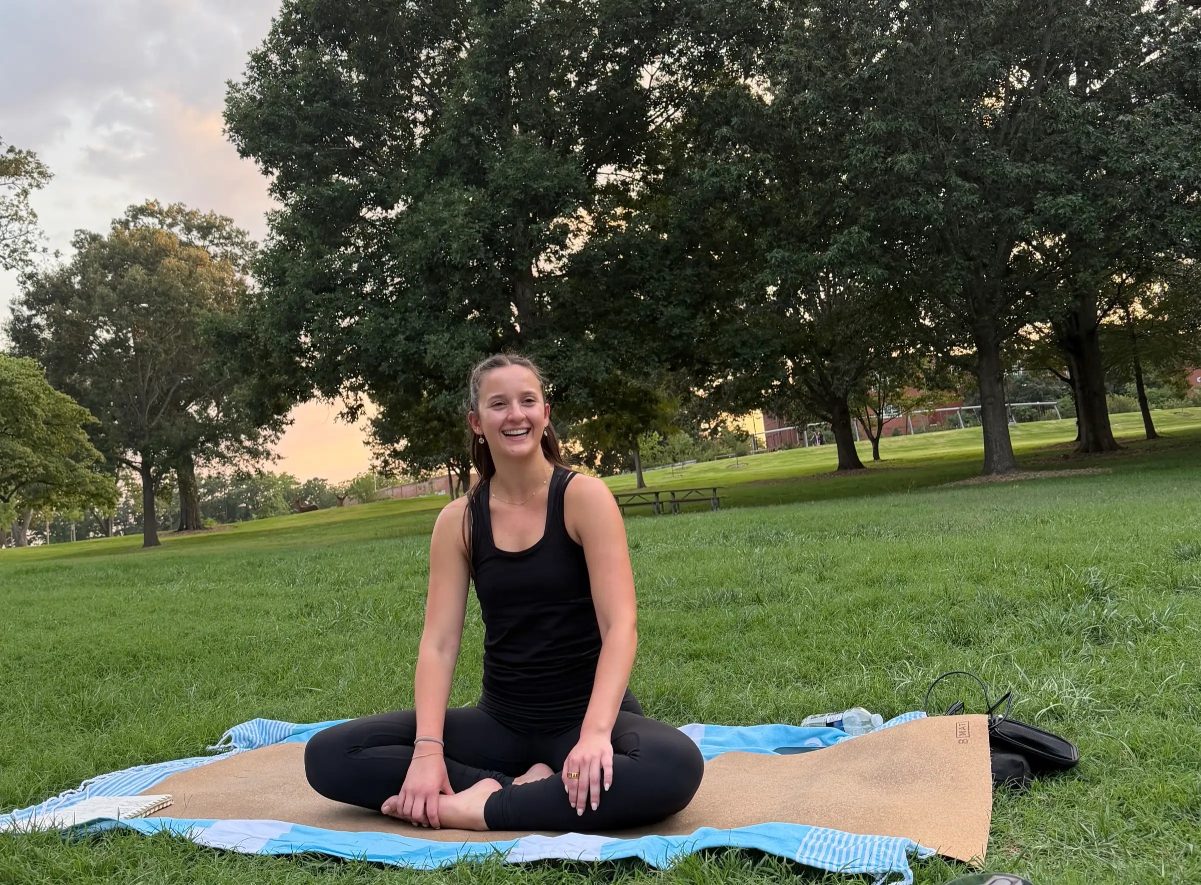 Michaela teaching a free outdoor yoga class in a park at sunset